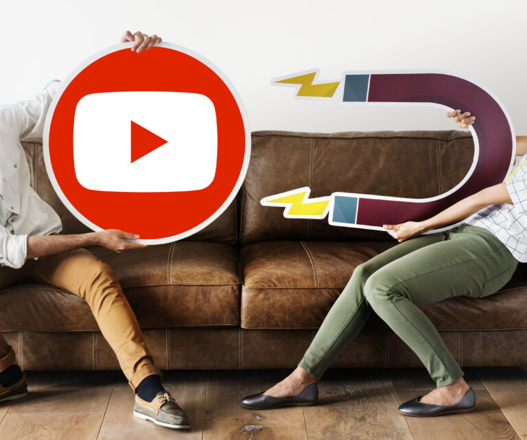 Two people holding a YouTube logo and a magnet to attract viewers with SEO.